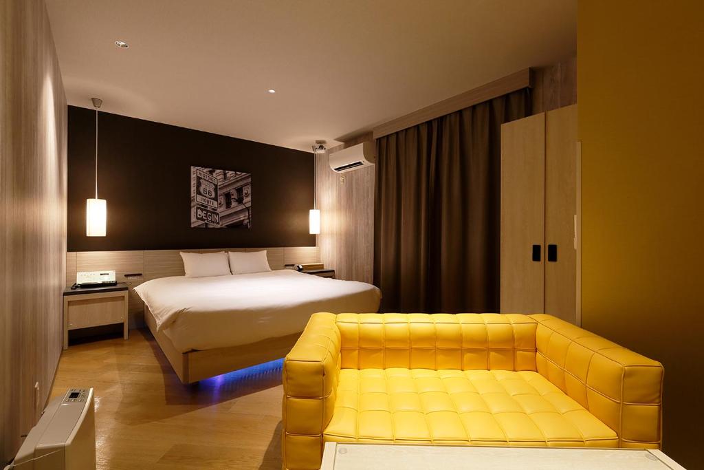 une chambre d'hôtel avec un lit et un canapé jaune dans l'établissement 555 MOTEL GOTEMBA, à Gotemba