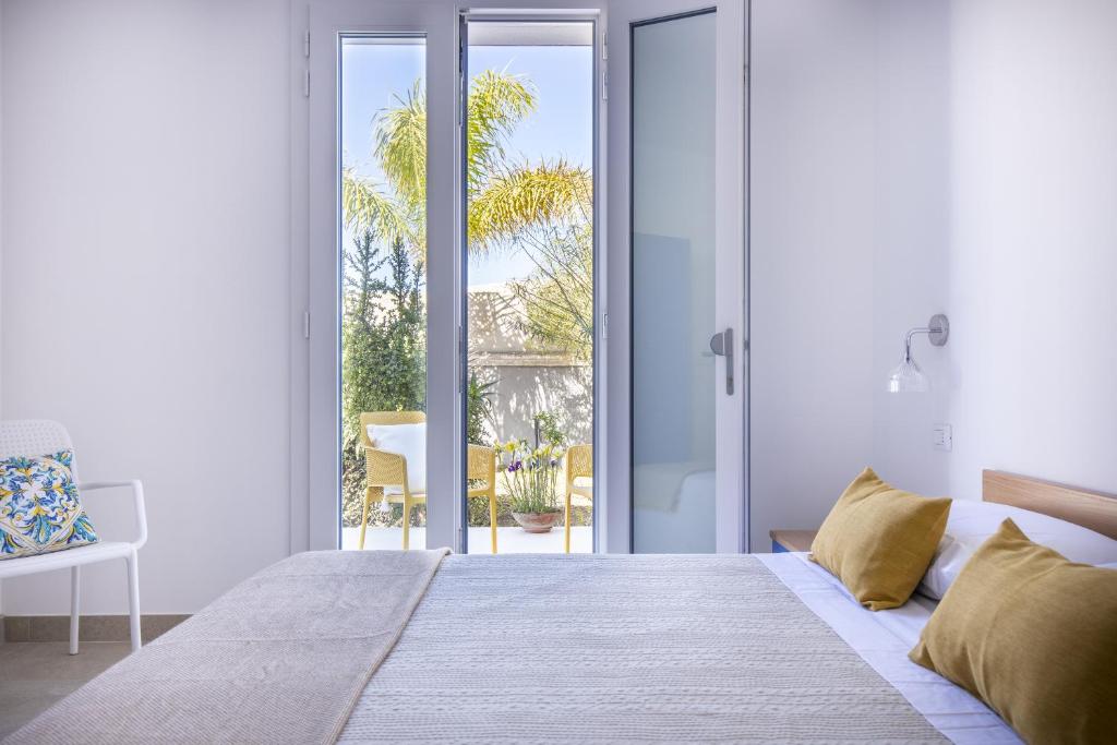- une chambre blanche avec un lit et une porte coulissante en verre dans l'établissement Le Perseidi Eco Home San Lorenzo, à Reitani