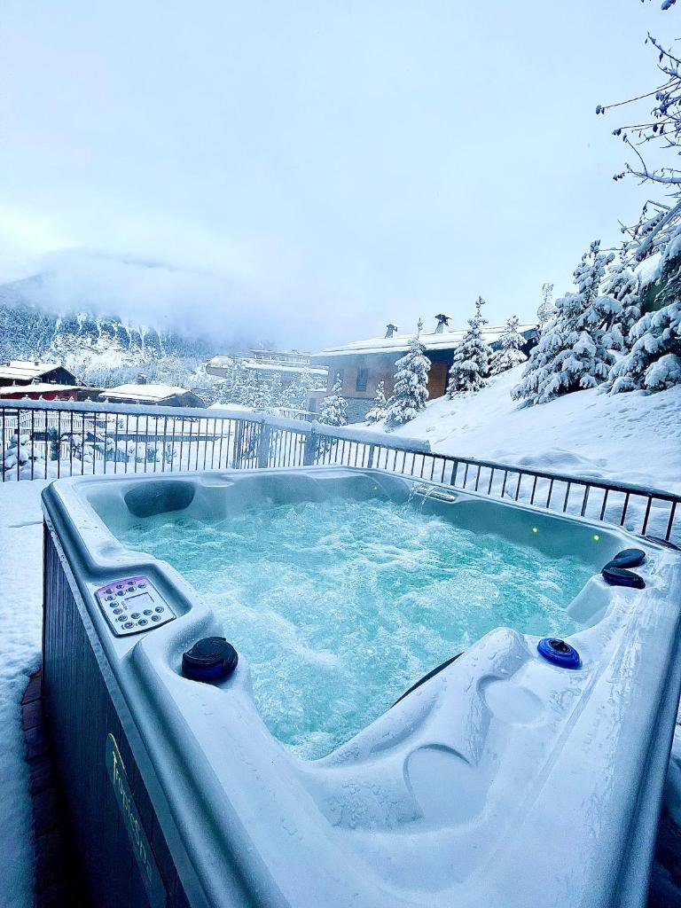 un bain à remous recouvert de neige dans une cour dans l'établissement Luxueux appartement skis aux pieds, jacuzzi privatif, à Courchevel
