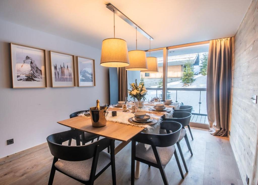 une salle à manger avec une table et des chaises en bois dans l'établissement Luxueux appartement skis aux pieds, jacuzzi privatif, à Courchevel