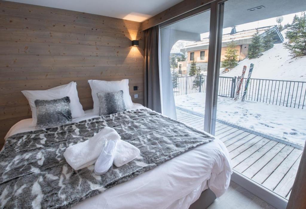 une chambre avec un lit et une grande fenêtre dans l'établissement Luxueux appartement skis aux pieds, jacuzzi privatif, à Courchevel