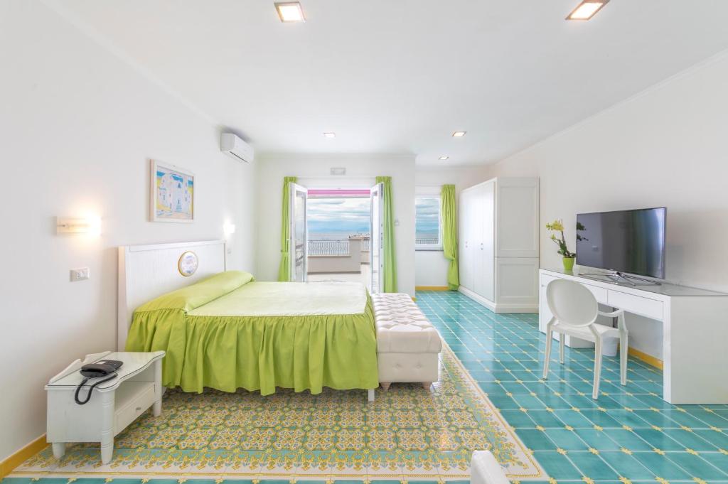 une chambre avec un lit, un bureau et une télévision dans l'établissement Hotel La Madonnina, à Ischia