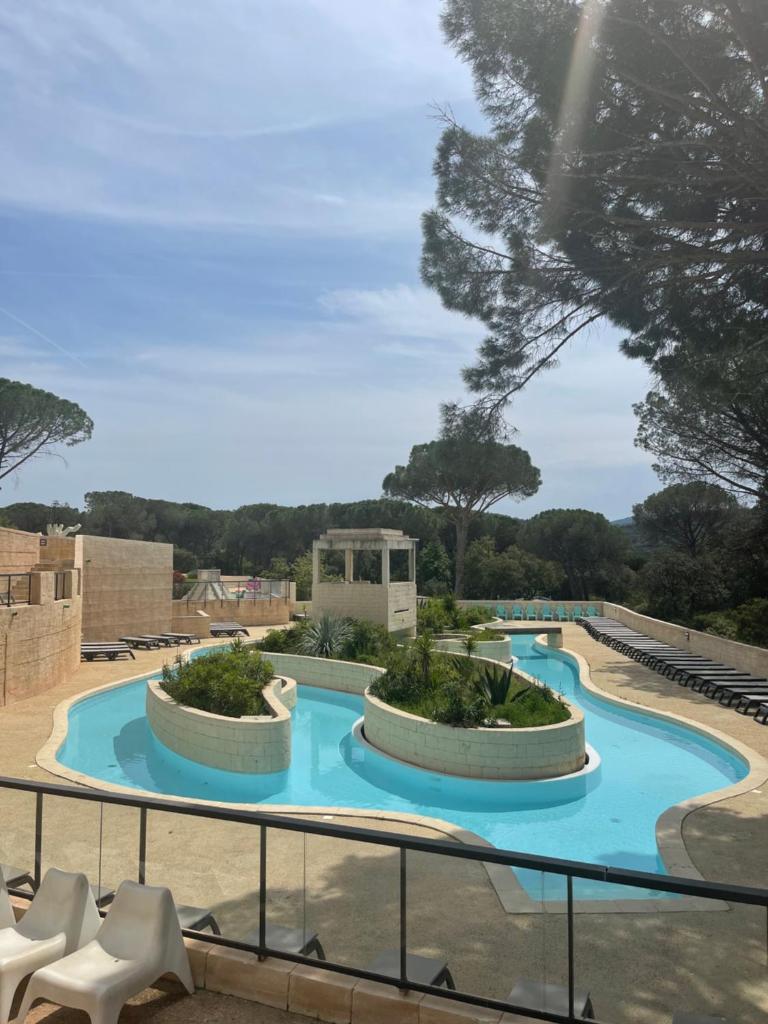une vue sur une piscine avec des chaises et des arbres dans l'établissement Camping les Cigales - Mobil-home 4/6 personnes, au Muy