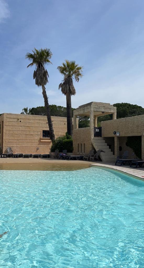 une piscine devant un immeuble avec des palmiers dans l'établissement Camping les Cigales - Mobil-home 4/6 personnes, au Muy