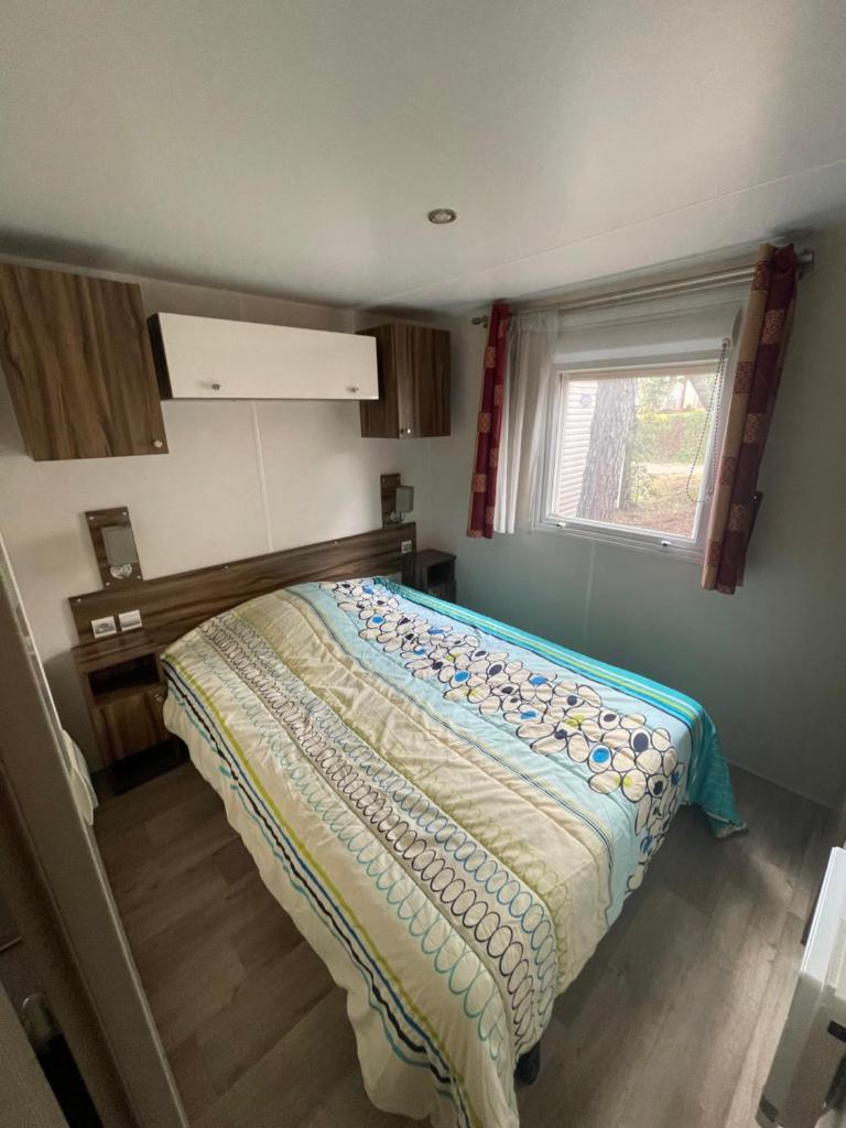 une chambre avec un lit dans une pièce avec une fenêtre dans l'établissement Camping les Cigales - Mobil-home 4/6 personnes, au Muy