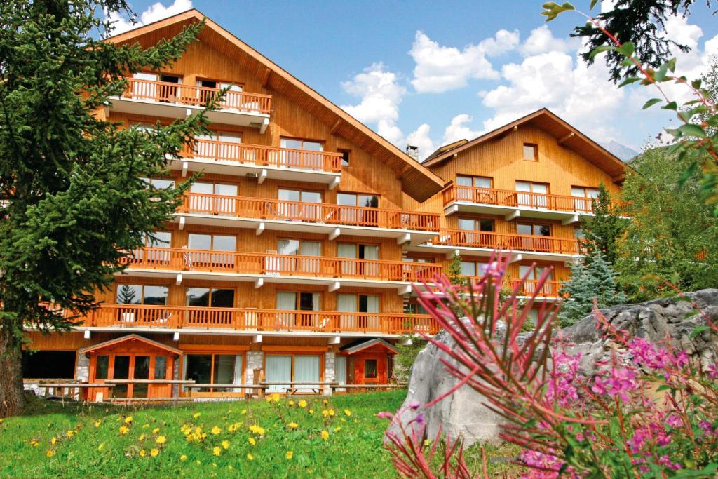 - un grand bâtiment avec des balcons, des arbres et des fleurs dans l'établissement Résidence partenaire Le Golf, à Méribel