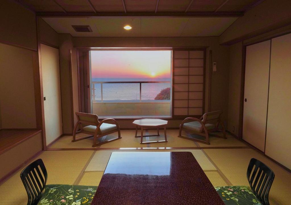 une pièce avec une table et des chaises et une grande fenêtre dans l'établissement Musashi, à Shirahama