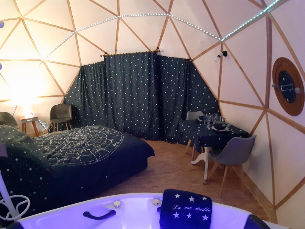 Cette chambre comprend une baignoire, un lit et une table. dans l'établissement Dôme La vue étoilée, à Poinson-lès-Fays 2 autres photos