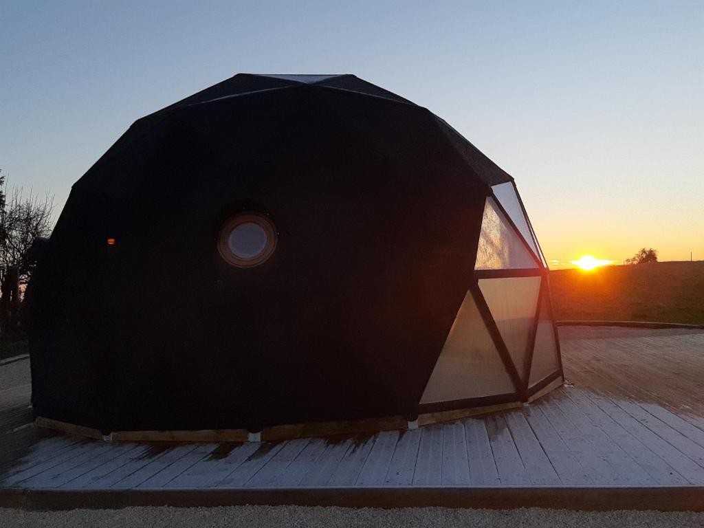 une tente noire avec le coucher du soleil en arrière-plan dans l'établissement Dôme La vue étoilée, à Poinson-lès-Fays