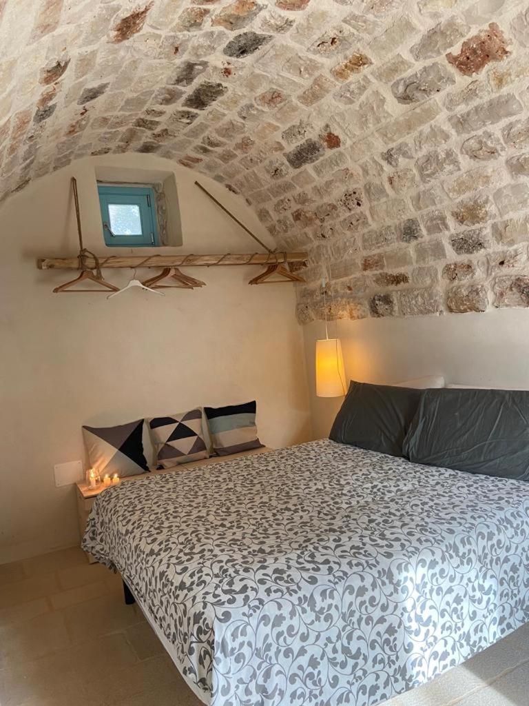 une chambre avec un lit et un mur en pierre dans l'établissement Trulli di Charme Eutuxia, à Villa Castelli