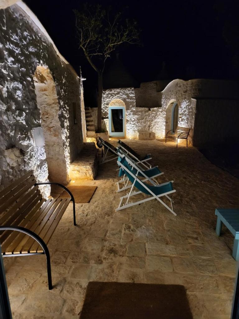 un groupe de bancs devant un bâtiment la nuit dans l'établissement Trulli di Charme Eutuxia, à Villa Castelli