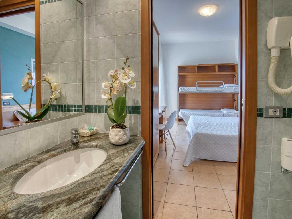 une salle de bain avec un lavabo et une chambre avec un lit dans l'établissement Hotel Colorado Cesenatico, à Cesenatico