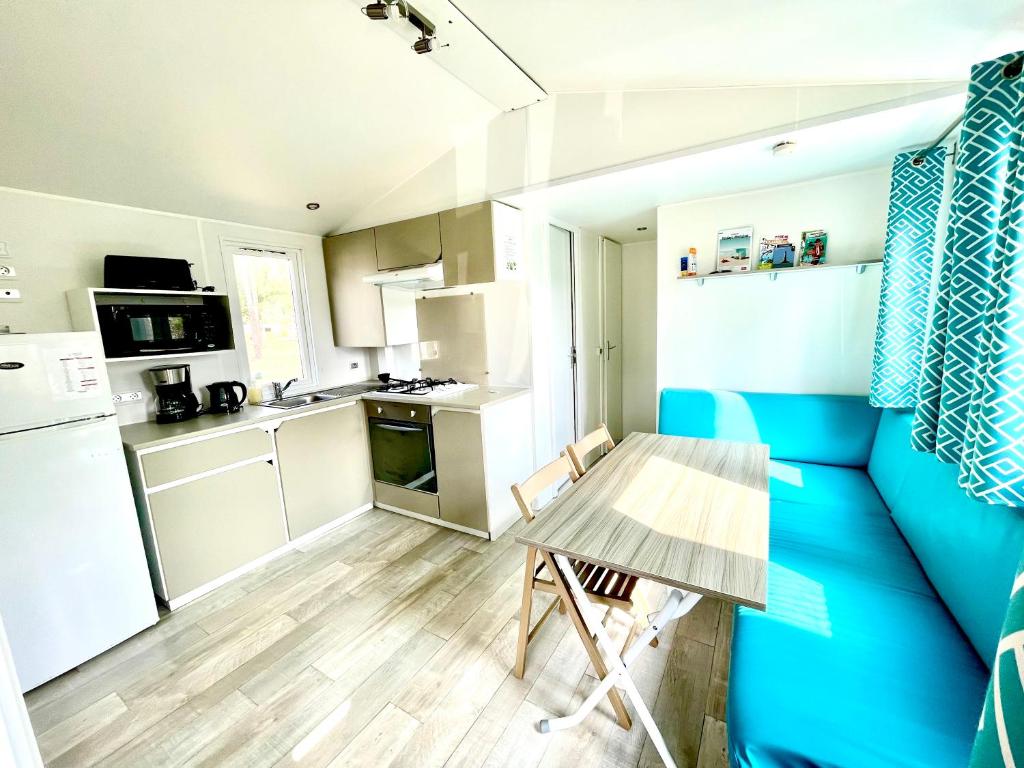 une petite cuisine avec une table et un mur bleu dans l'établissement Spacieux Mobilhome Premium/Camping 5*, à Vendays-Montalivet