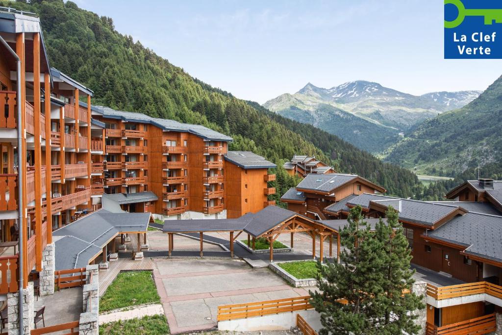 un groupe de bâtiments avec des montagnes en arrière-plan dans l'établissement Résidence Pierre & Vacances Premium les Crets, à Les Allues