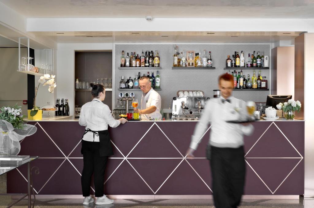 un couple de personnes debout à un bar dans l'établissement Hotel Castello Lake Front, à Malcesine