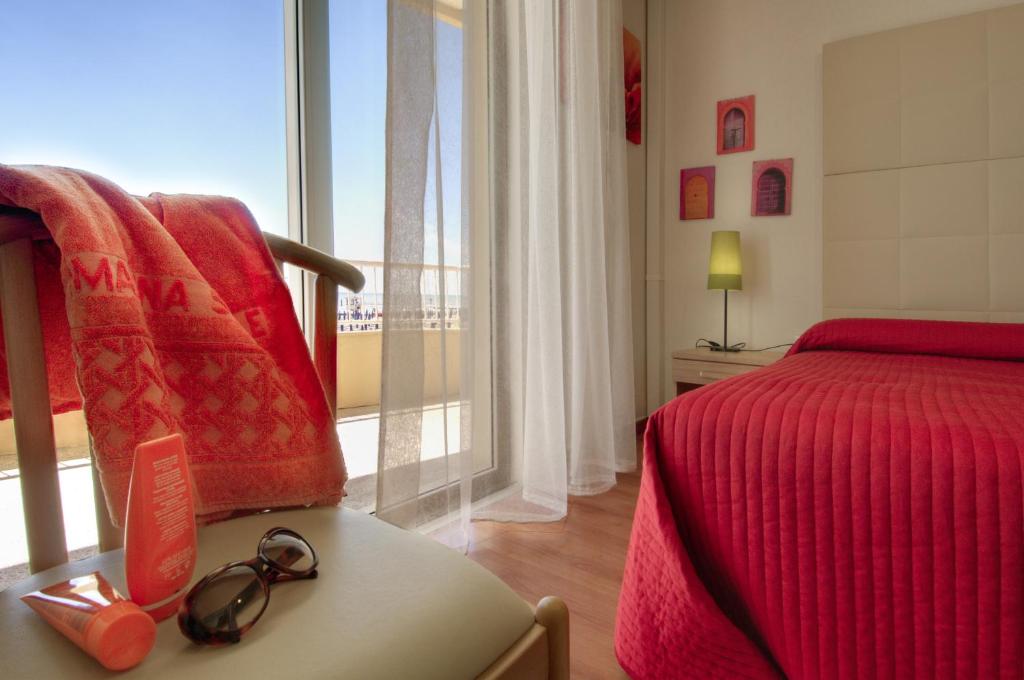 une chambre avec un lit rouge et une fenêtre dans l'établissement Hotel Telenia, à Lido di Jesolo