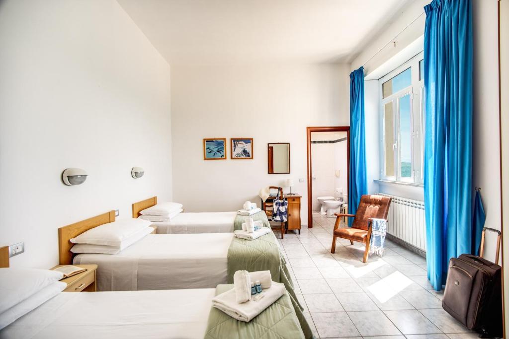 une chambre d'hôtel avec deux lits et une chaise dans l'établissement Villa MG Hotel, à Santa Marinella