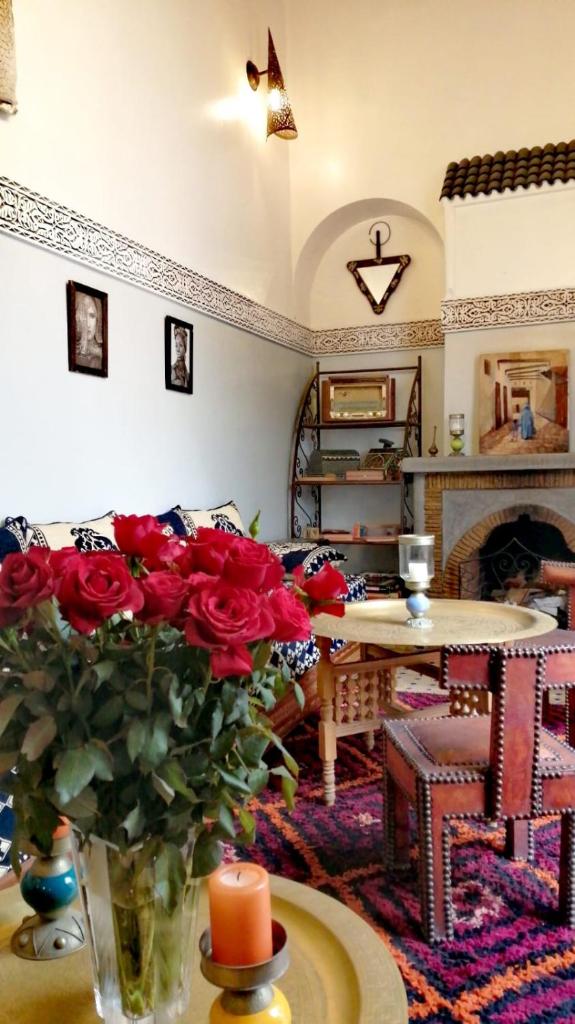 un salon avec un vase de roses sur une table dans l'établissement Riad Attarine, à Fès