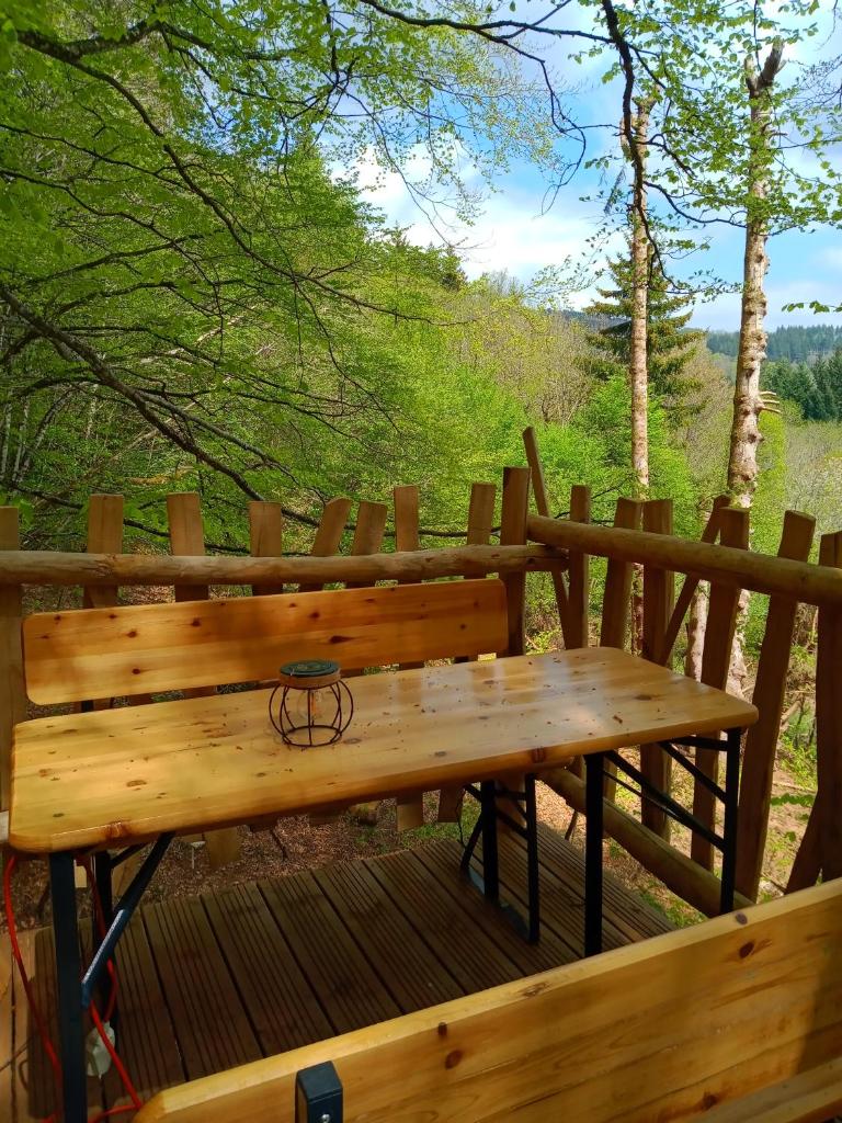 un banc en bois installé au-dessus d'une terrasse en bois dans l'établissement Cabane du Druide Domaine de Fangorn, à Glux