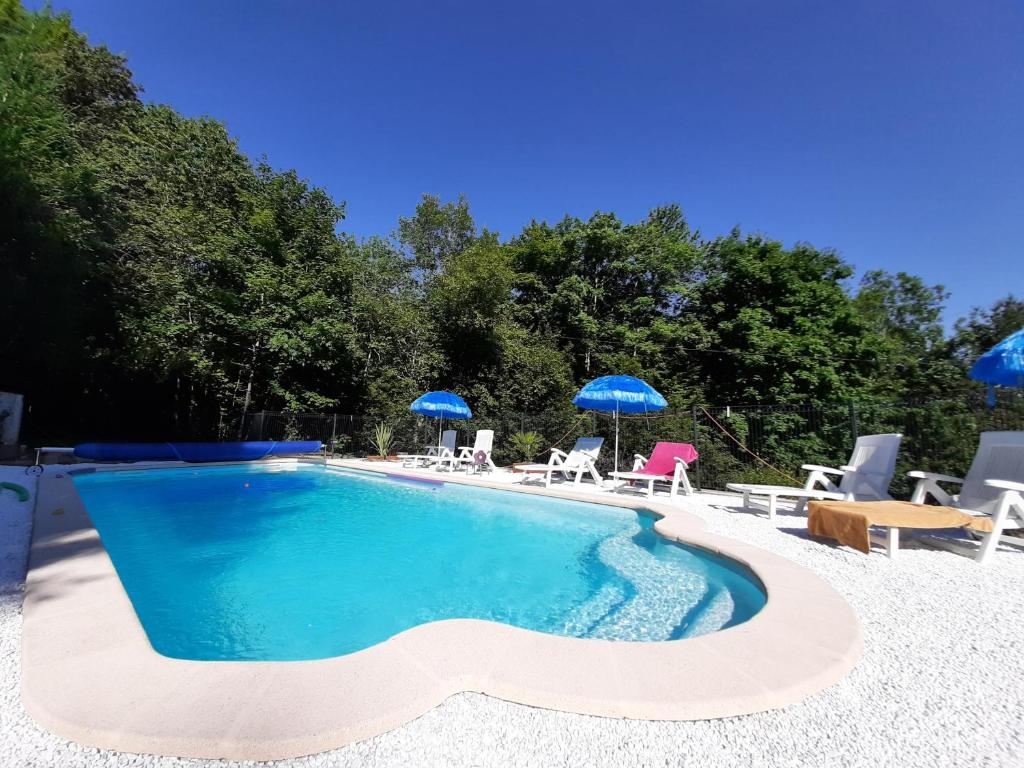 une piscine avec chaises et parasols dans une cour dans l'établissement Cabane du Druide Domaine de Fangorn, à Glux
