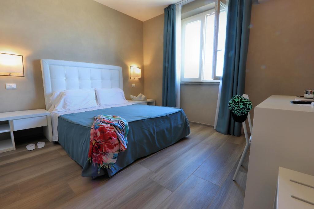 une chambre avec un lit avec des draps bleus et une fenêtre dans l'établissement Hotel Cecina Beach, à Marina di Cecina