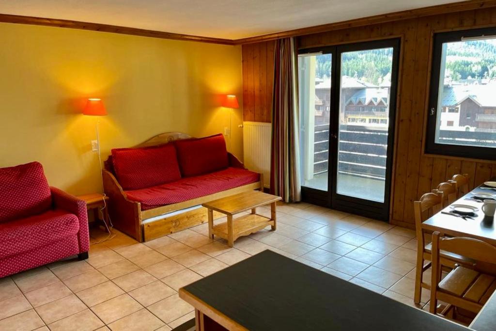 Il comprend un salon doté d'un mobilier rouge et d'un balcon. dans l'établissement Confortable appt de 55 m avec BALCON-VUE, à Chamonix-Mont-Blanc
