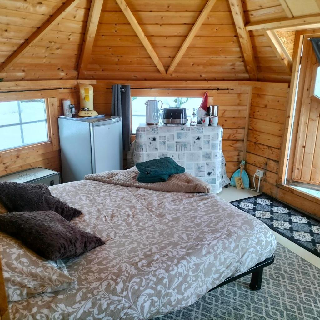 une chambre avec un lit dans une cabane en bois dans l'établissement Cabane des lutins - Belle Fleur, à Saint-Nabord