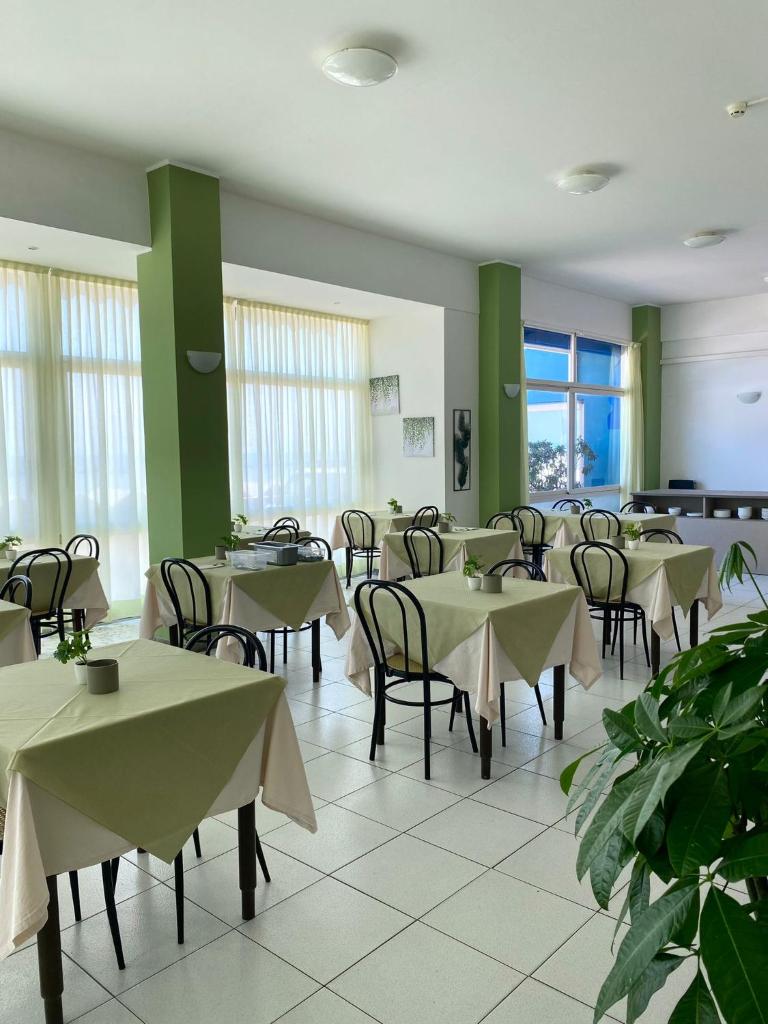 une salle à manger avec tables, chaises et fenêtres dans l'établissement HOTEL FLYING, à Pesaro