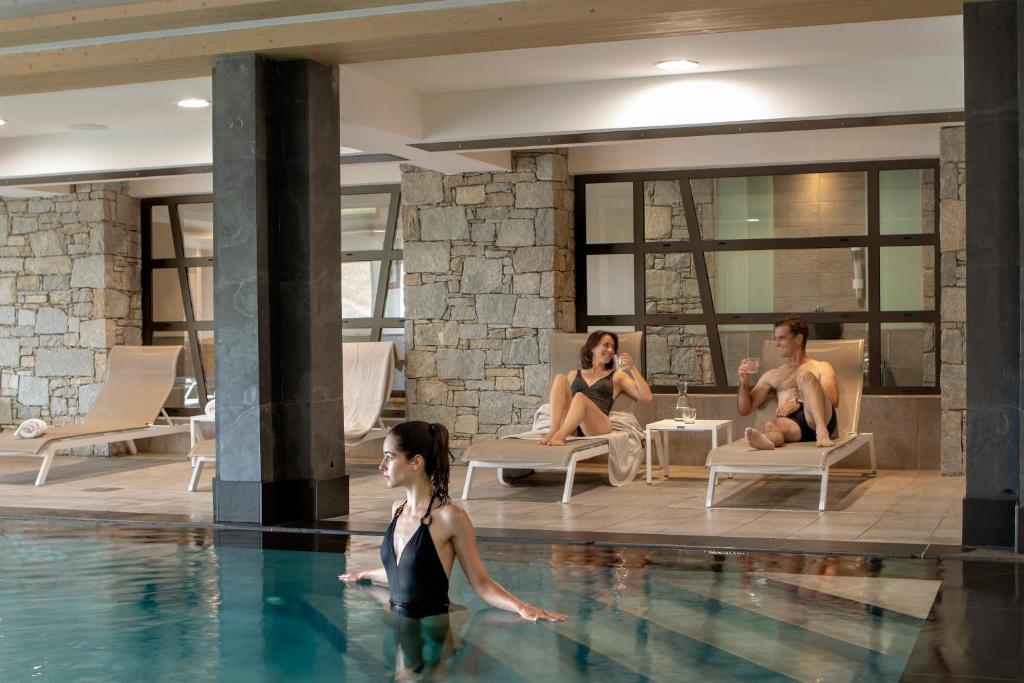 un groupe de personnes assises dans une piscine dans l'établissement MGM Hôtels & Résidences - Résidence Le Roc Des Tours, au Grand-Bornand