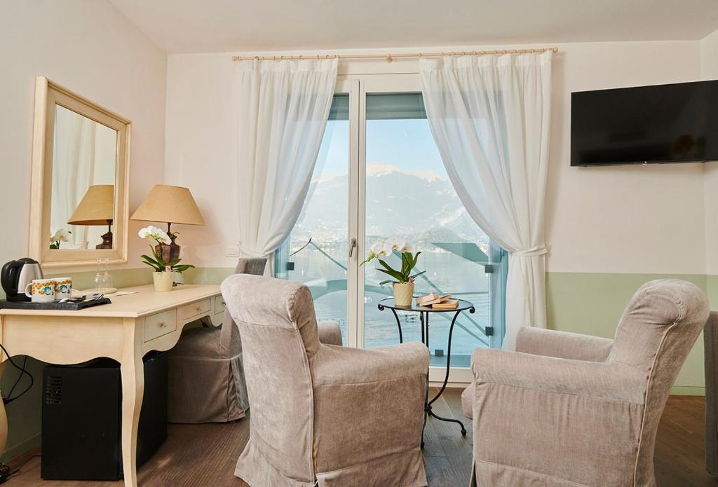 Cette chambre dispose d'un bureau, de chaises et d'une fenêtre. dans l'établissement Hotel Villa Aurora, à Lezzeno