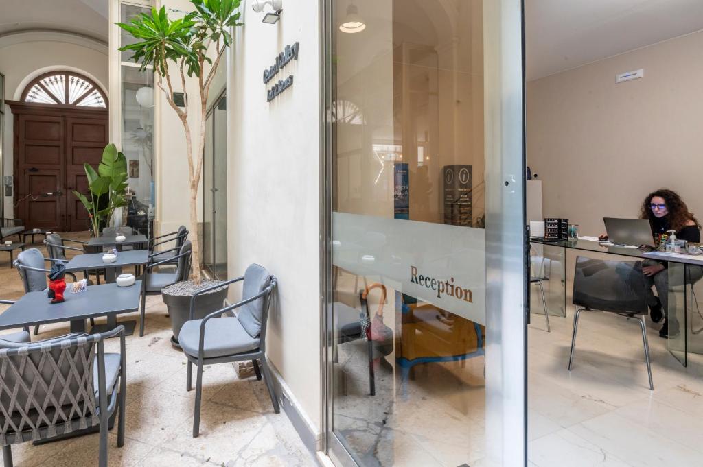 une femme assise à une table avec un ordinateur portable dans un restaurant dans l'établissement Central Gallery Rooms- Palazzo D'Ali' Staiti XIX, à Trapani