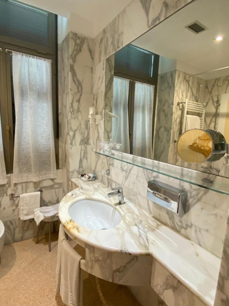 une salle de bain avec un lavabo et un miroir dans l'établissement Hotel Parigi & Spa, à Bordighera