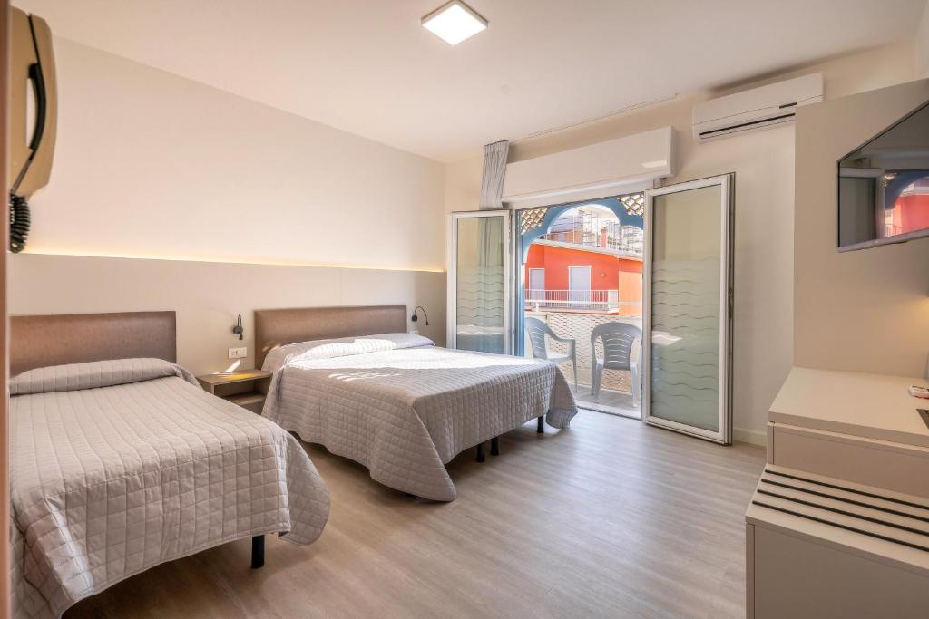 une chambre d'hôtel avec deux lits et un balcon dans l'établissement Hotel Maxim, à Caorle