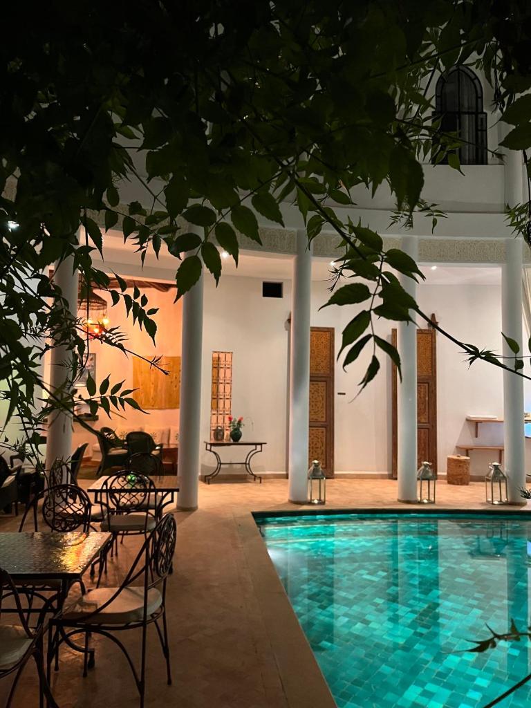 - une piscine dans une pièce avec des chaises et une table dans l'établissement Riad Chergui, à Marrakech