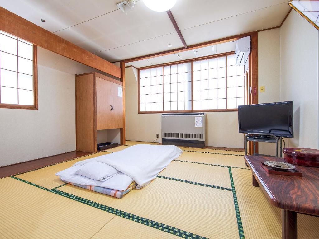 Cette grande chambre comprend un lit et une télévision. dans l'établissement Ohmachiso, à Akita