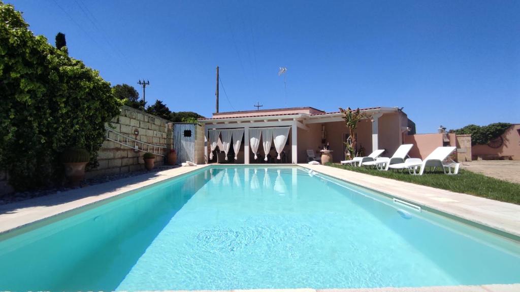 une piscine avec des chaises et une maison dans l'établissement La Vigna Salentina - Con Giardino e Piscina Privata, à Alessano