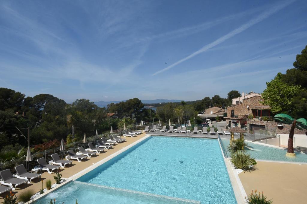 une piscine avec des chaises longues et un complexe hôtelier dans l'établissement Mobil Home Vue sur Mer - Racine 03, à Saint-Raphaël