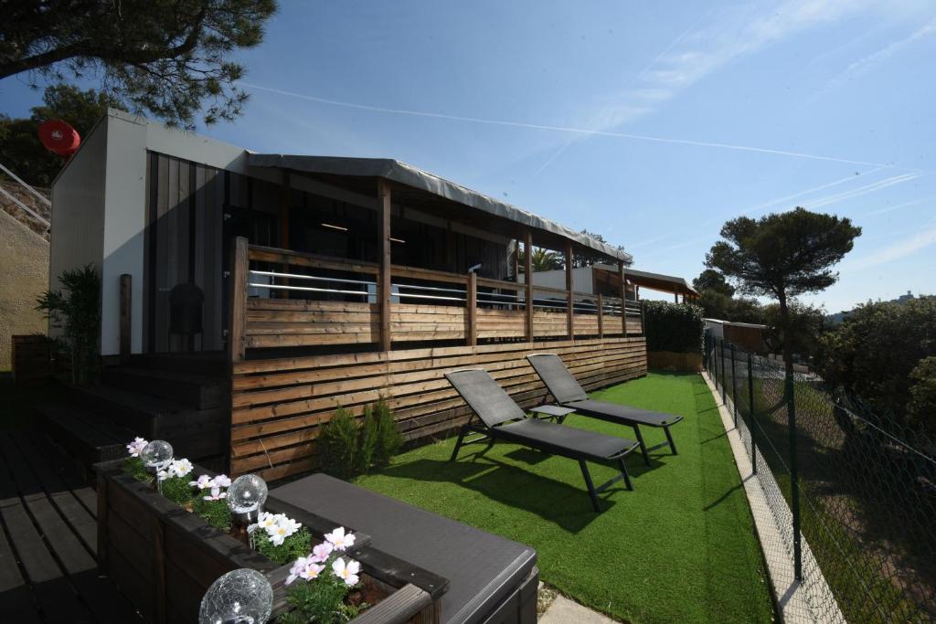 une arrière-cour avec deux chaises et une maison dans l'établissement Mobil Home Vue sur Mer - Racine 03, à Saint-Raphaël