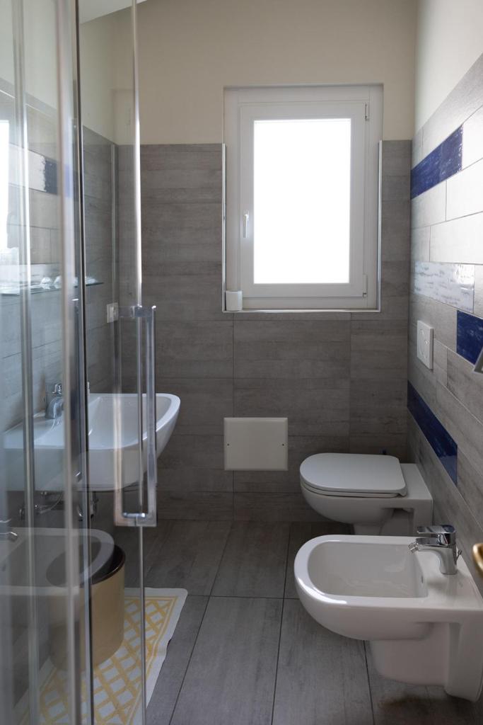 une salle de bain avec deux lavabos et un WC et une fenêtre dans l'établissement La Foresta Monteisola, à Monte Isola