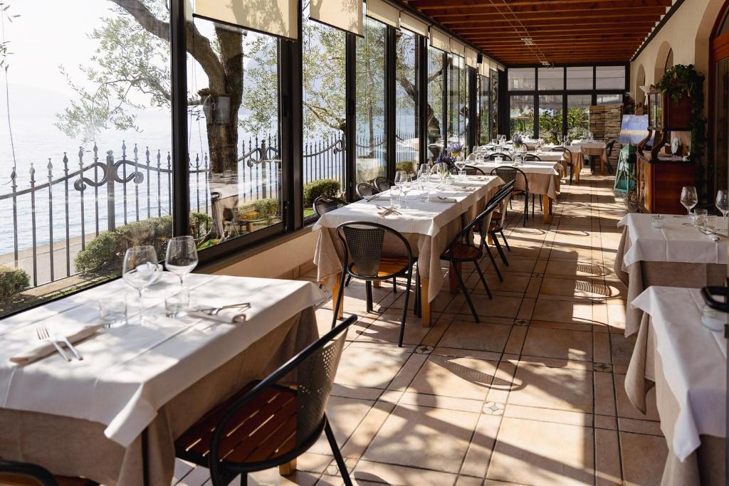 une rangée de tables dans un restaurant avec fenêtres dans l'établissement La Foresta Monteisola, à Monte Isola