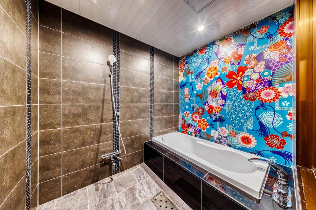 La salle de bains est pourvue d'une baignoire et d'un mur en carrelage. dans l'établissement Hotel Lotus Gorgeous Japan Kyoto -Adult Only, à Kyoto