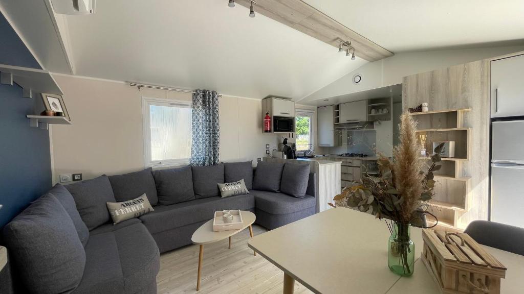 un salon avec un canapé bleu et une table dans l'établissement Mobil home XXL - Bord LAC - CAMPING Les Viviers - Lège cap ferret, à Lège-Cap-Ferret