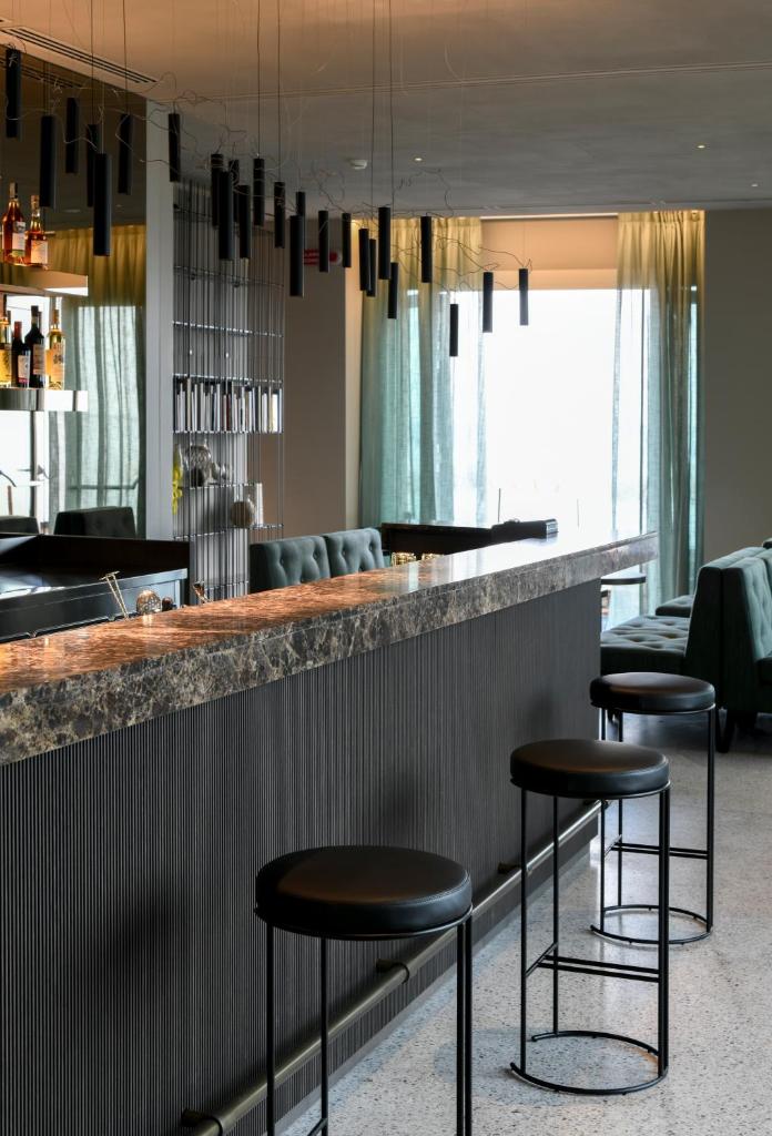 un bar avec deux tabourets devant un comptoir dans l'établissement Hotel Windsor, à Laigueglia