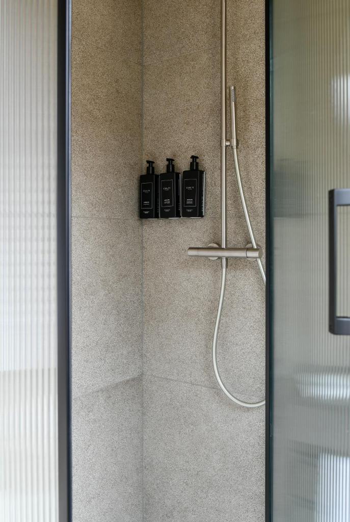 une salle de bain avec une douche avec quatre bouteilles au mur dans l'établissement Hotel Windsor, à Laigueglia