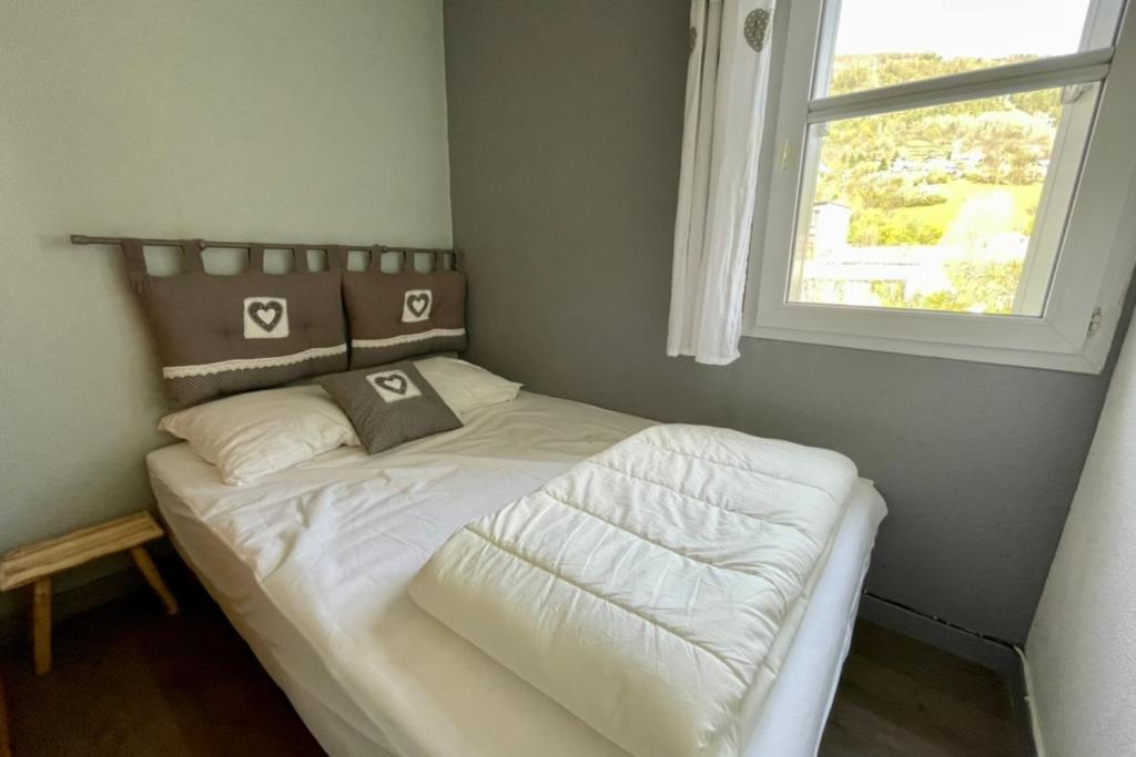une chambre avec un lit avec des draps blancs et une fenêtre dans l'établissement LUMINEUX 50 m avec BALCON au centre de Briançon, à Briançon