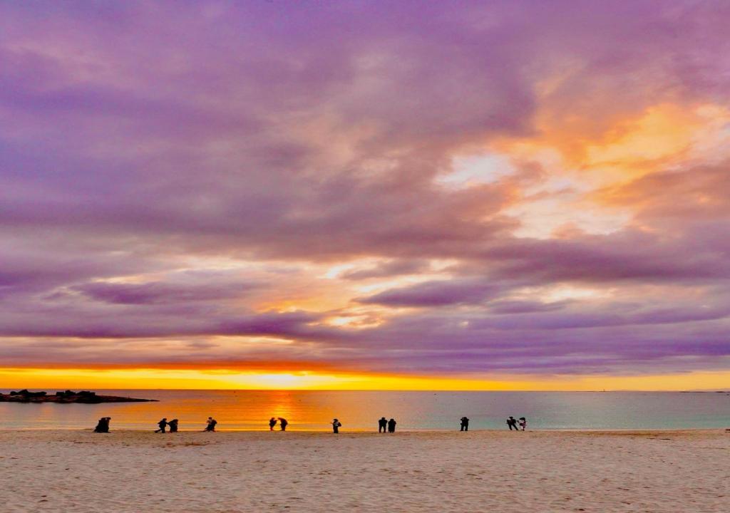 - un groupe de personnes debout sur une plage au coucher du soleil dans l'établissement Musashi, à Shirahama