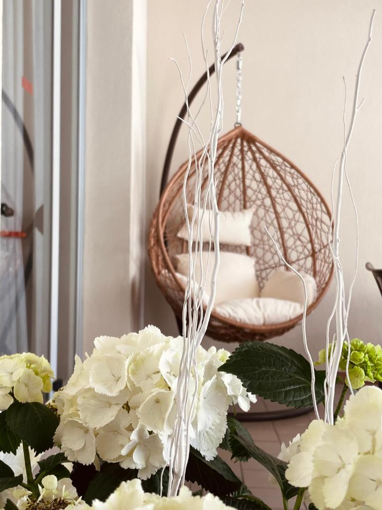 une chaise en osier dans une chambre ornée de fleurs blanches dans l'établissement Hotel Vera, à Cesenatico