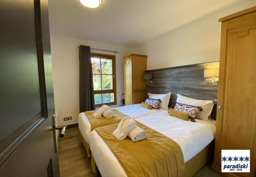 une chambre avec un grand lit avec des serviettes dessus dans l'établissement Stylish ski-in ski-out 3 bed apartment, Arc 1950, à Arc 1950