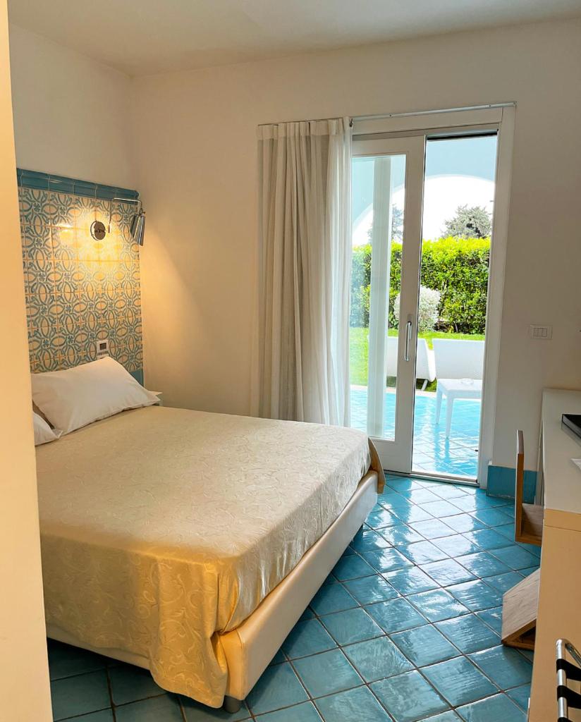 une chambre avec un lit et une porte coulissante en verre dans l'établissement Ganimede Hotel, à Sperlonga