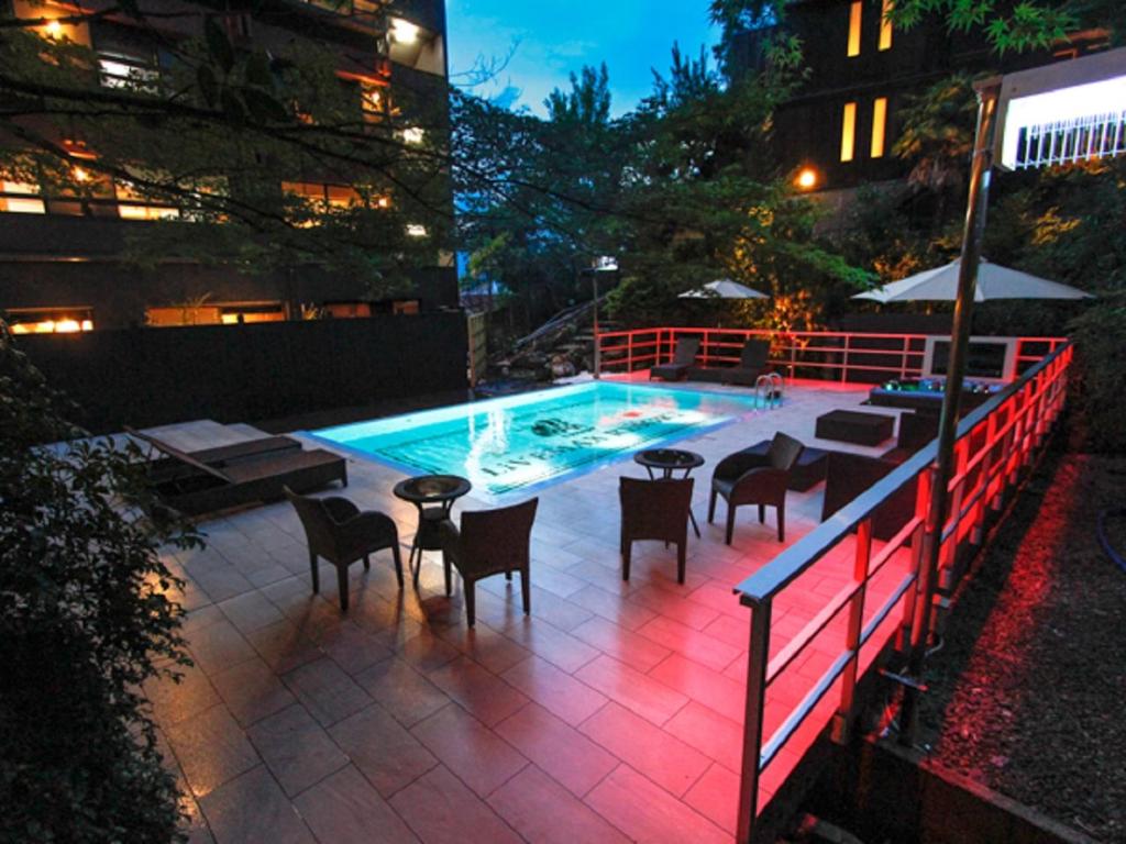 - une piscine avec des tables et des chaises à côté d'un bâtiment dans l'établissement LiVEMAX RESORT Aki Miyajima, à Miyajima